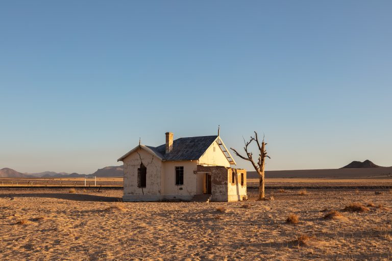 Sand-covered abandoned railway station near Kolmanskop, Namibia with derelict tracks disappearing into the desert.